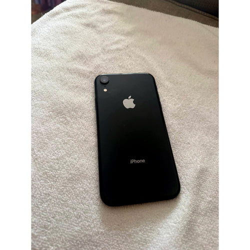Back view of used Apple iPhone XR in Black with single rear camera and Apple logo, laid on a white towel
