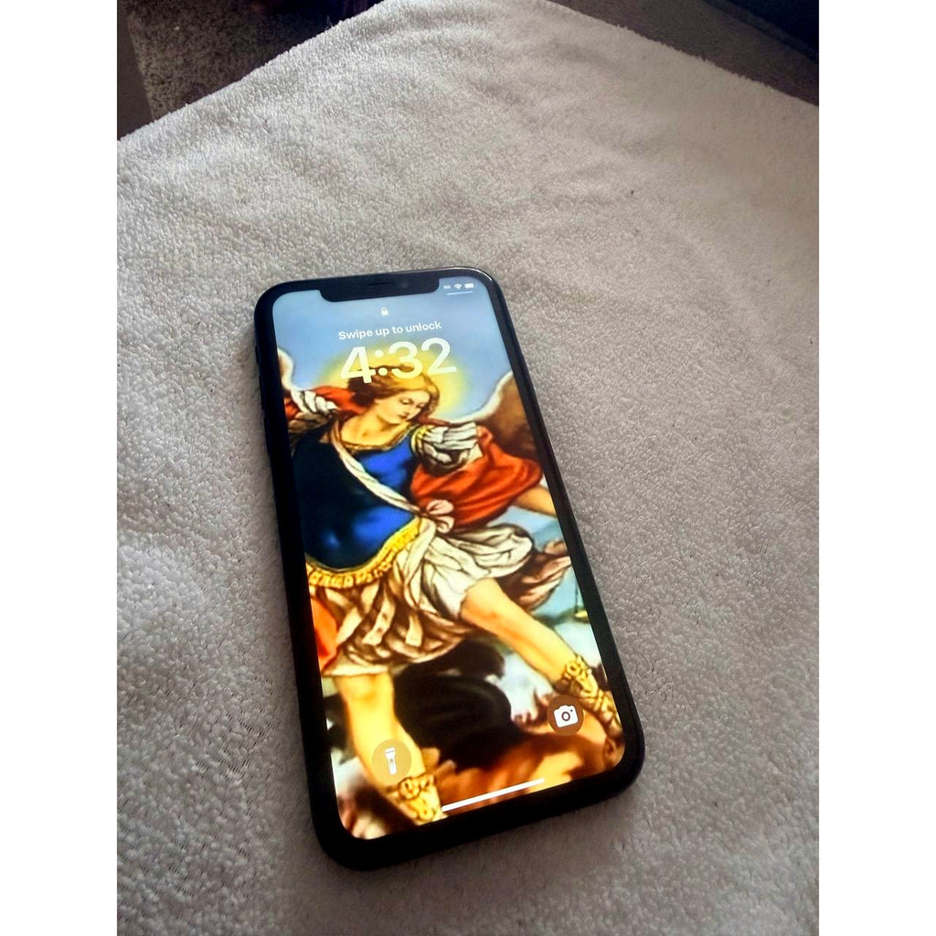 Front view of used Apple iPhone XR in Black showing powered-on Liquid Retina display with lock screen, laid on a white towel